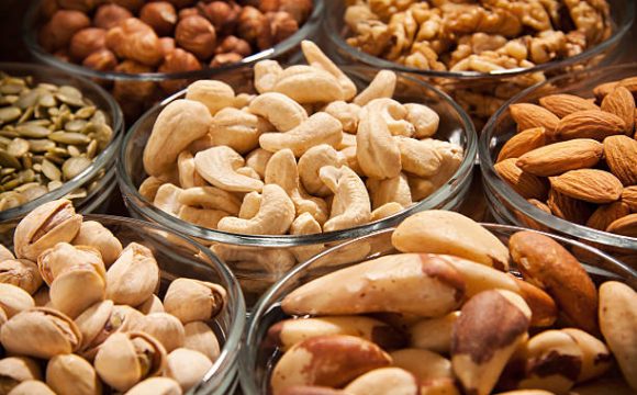 "Various snacks,nuts,and dryed fruits in glass dish bowles."